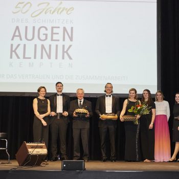 Ärtze und das Team der Augenklinik Kempten und des Laserzentrum Allgäu stehen während der Jubiläumsfeier auf der Bühne.