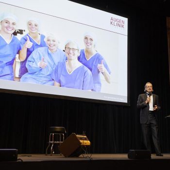 Bühnenmoment mit Präsentation und Würdigung bei der Jubiläumsfeier der Augenklinik Kempten.