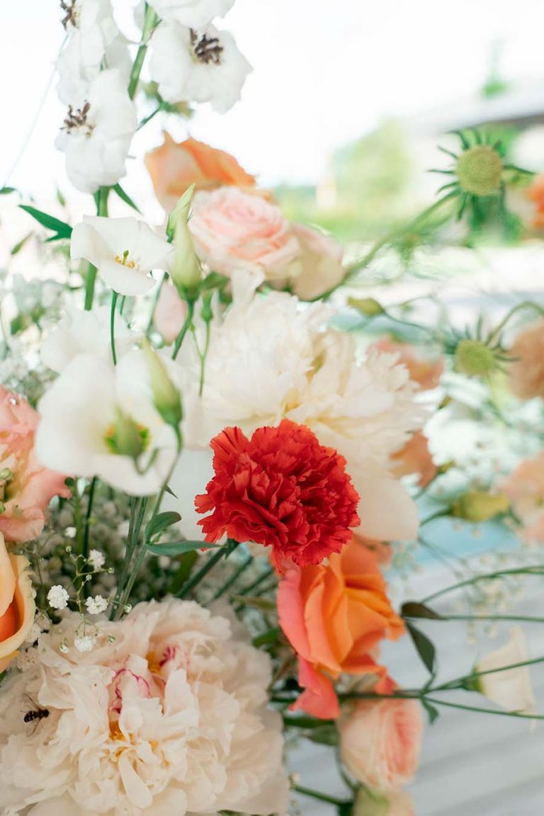 Blumenarrangement mit weißen und rosafarbenen Blüten sowie orangefarbenen Akzenten.