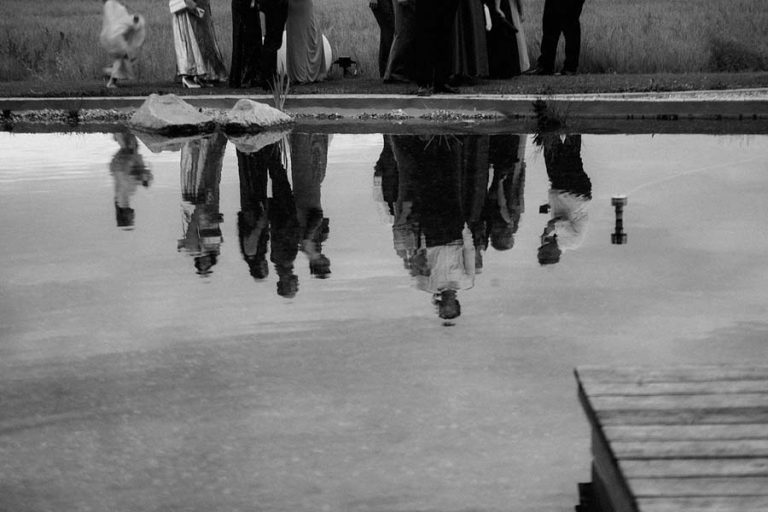 Spiegelung der Hochzeitsgesellschaft im Wasser, in Schwarz-Weiß.