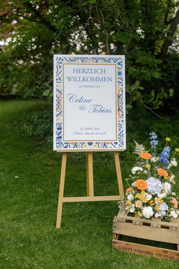 Willkommensschild Hochzeit auf Staffelei mit Blumenbouquet im Weingut