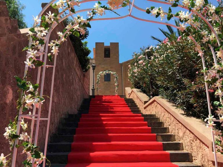 Roter Teppich auf der Treppe zur kirchlichen Trauung mit Blumenbögen in Italien