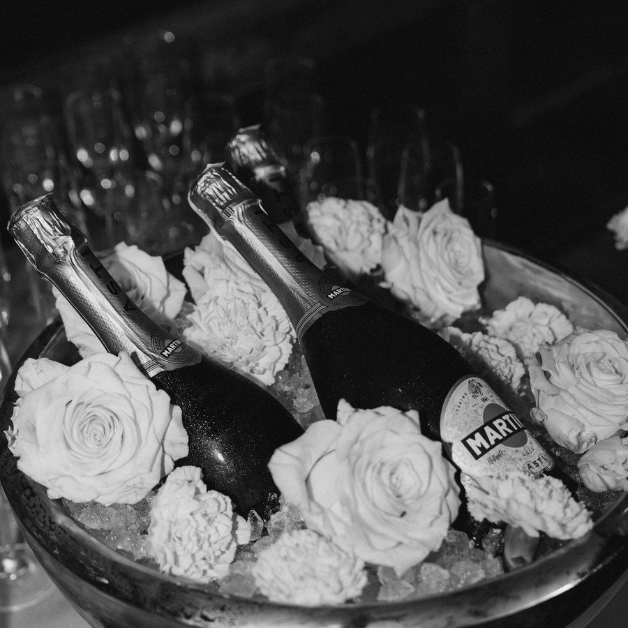 Eventplanung Allgäu: Champagnerflaschen im Sektkühler zwischen weißen Rosen, Schwarz-Weiß-Aufnahme