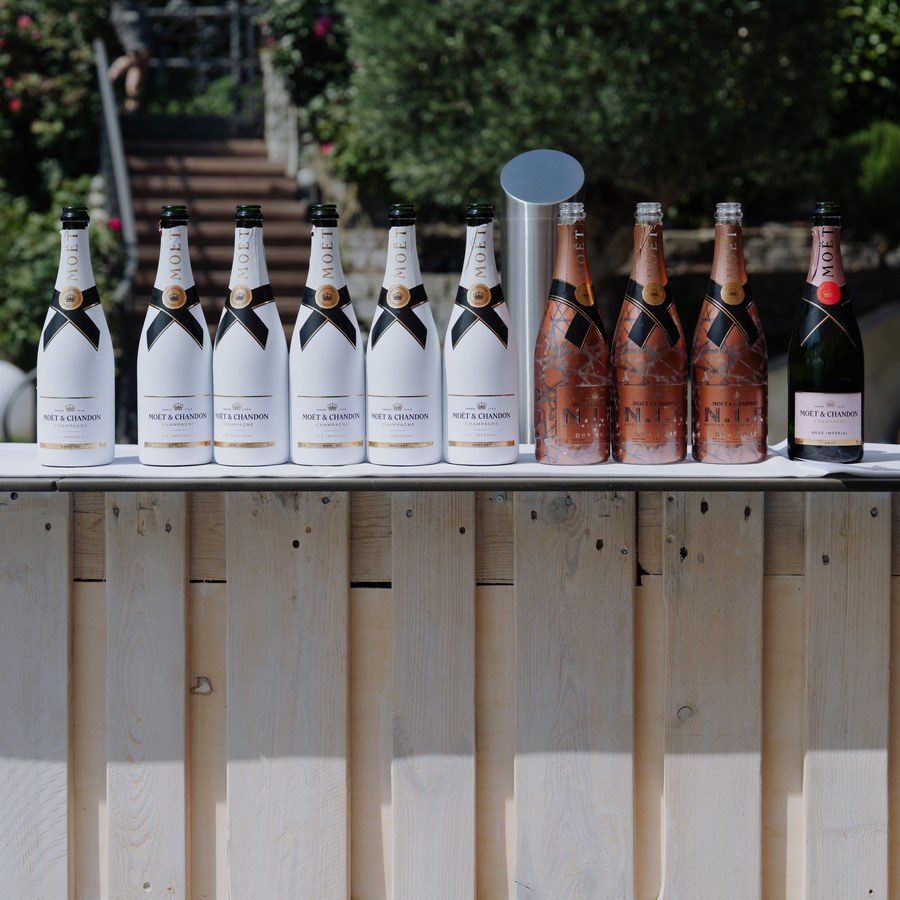 Eventplanung Bodensee: Champagnerflaschen aufgereiht auf einer Holzbar beim Empfang im Garten