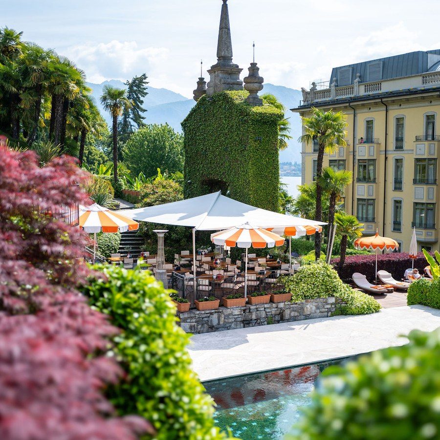 Eventplanung Comer See: Sonnenschirme und Liegen auf der Gartenterrasse am Pool, ringsum blühende Sträucher