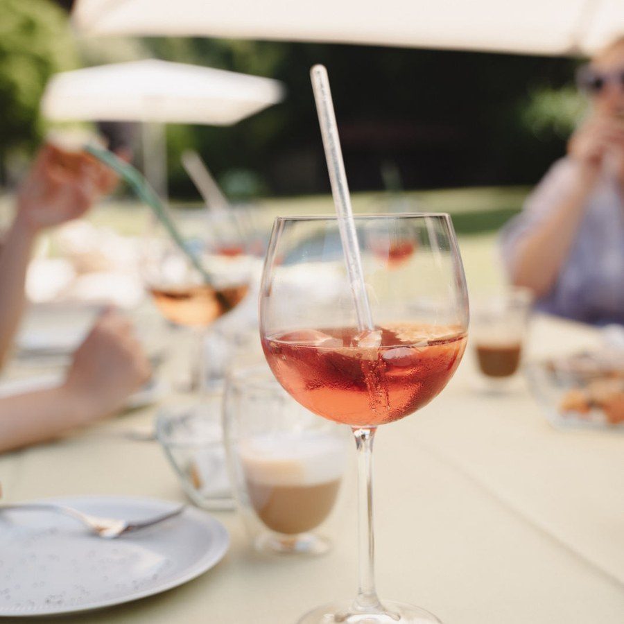 Eventplanung Gardasee: Aperitif im Weinglas auf der gedeckten Terrassentafel unter dem Sonnenschirm
