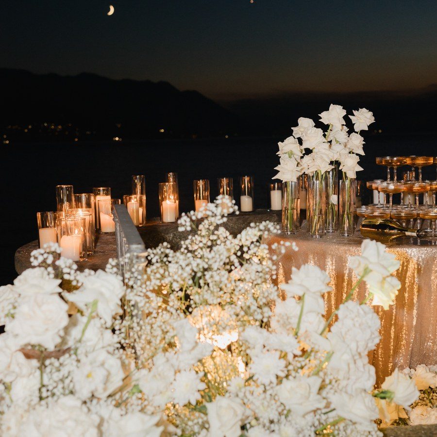 Eventplanung Lago Maggiore: Abendtafel mit weißen Blumen und Kerzenmeer über dem See unter der Mondsichel