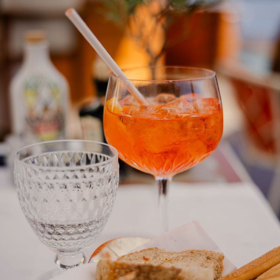 Eventplanung Mannheim: Spritz mit Strohhalm, Kristallglas und Brot auf einem gedeckten Tisch