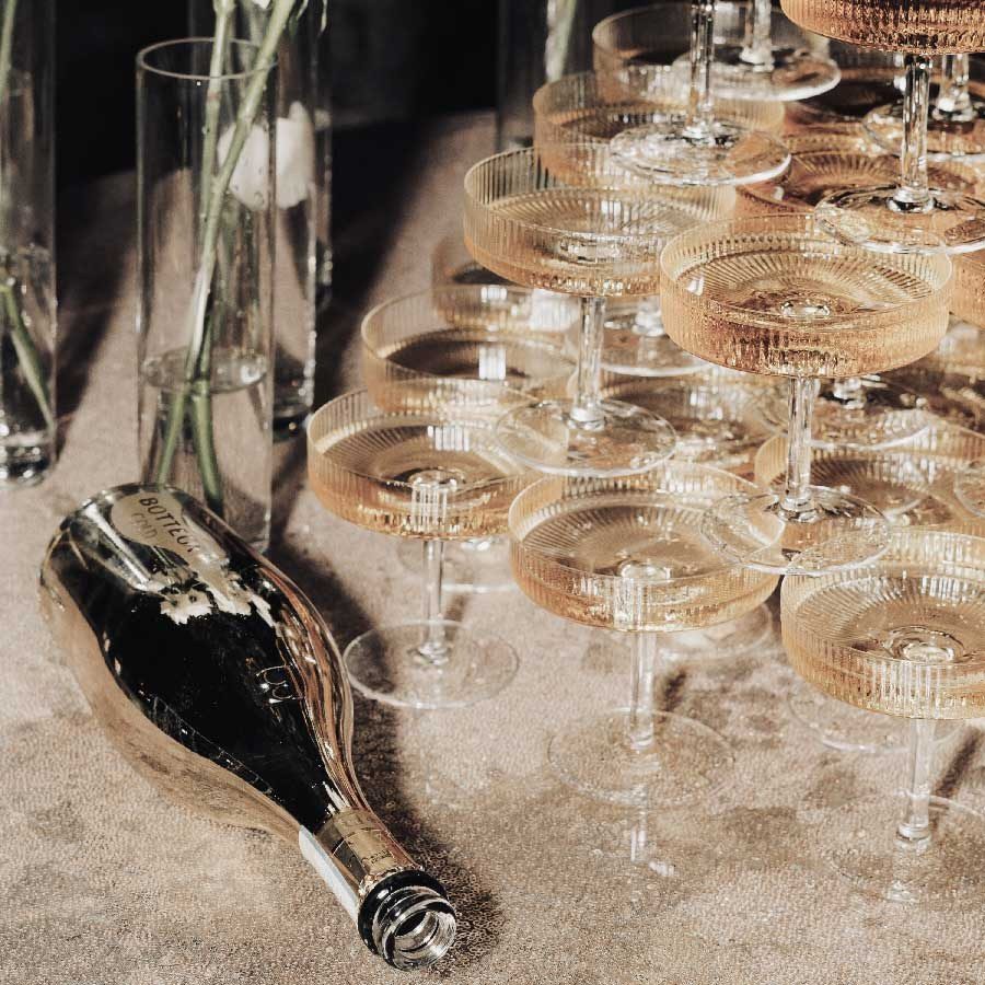 Eventplanung Neckar: Pyramide aus geriffelten Champagnerschalen mit einer liegenden goldenen Flasche
