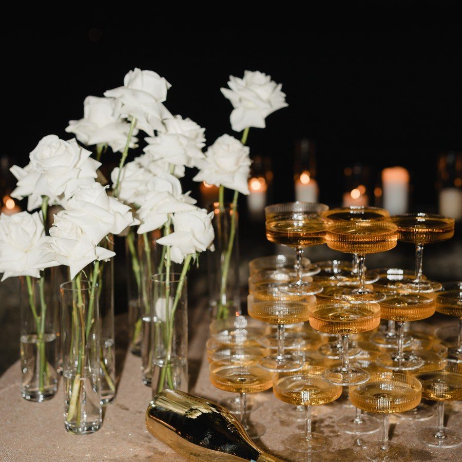 Eventplanung Schweiz: gestapelte Champagnerschalen zwischen weißen Rosen und Kerzen im Abendlicht