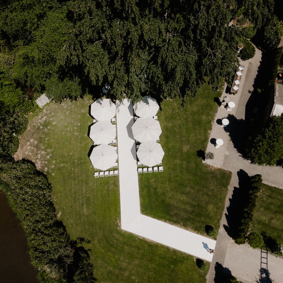 Freie Trauung Ingolstadt: Luftbild der Trauungsbestuhlung mit weißen Sonnenschirmen im Park am Wasser