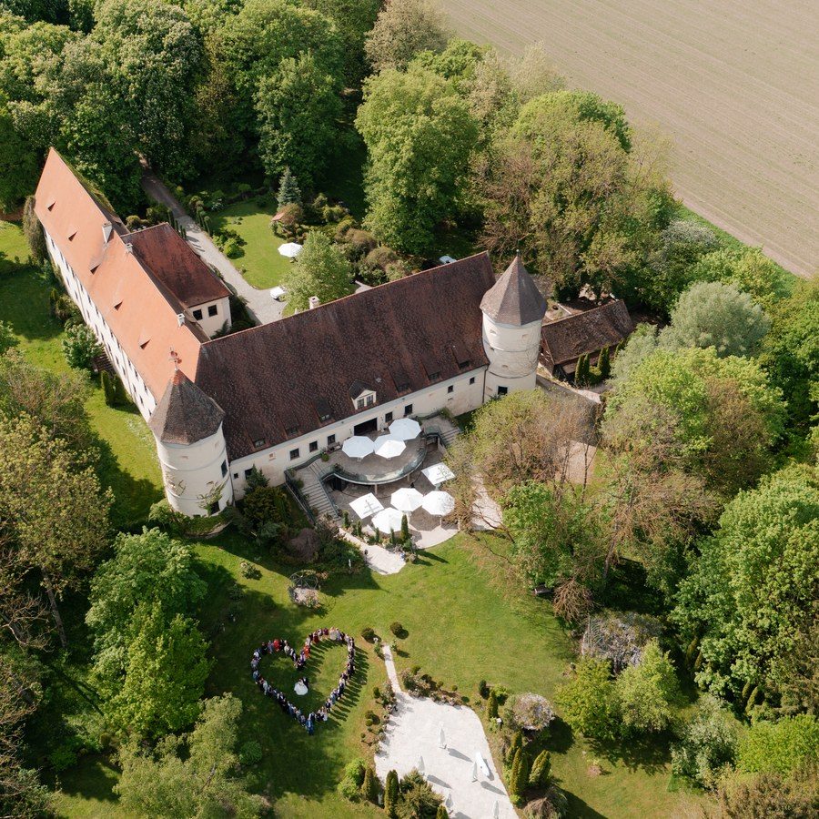 Luftbild eines Landguts im Grünen, im Park davor die Bestuhlung für eine freie Trauung