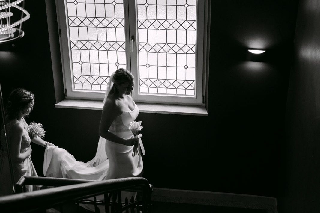 Hochzeit in NRW: Braut auf der Treppe vor Sprossenfenster in Schwarzweiß