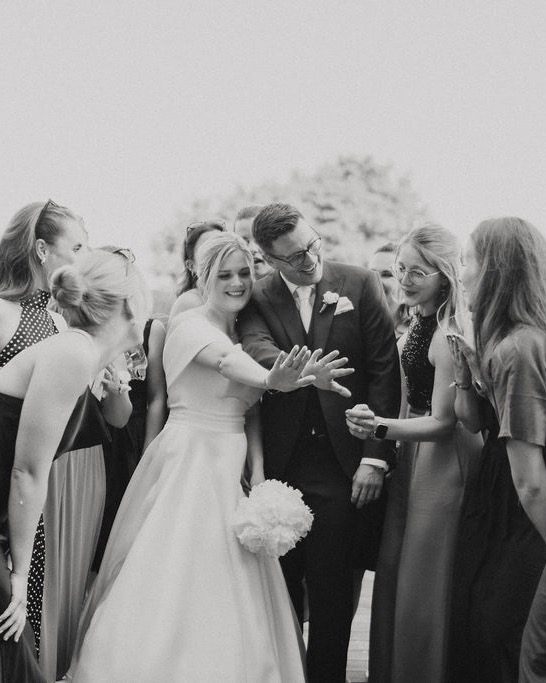 Hochzeitsplaner Ulm – Braut zeigt ihren Freundinnen den Ehering, Schwarz-Weiß-Aufnahme am Wasser