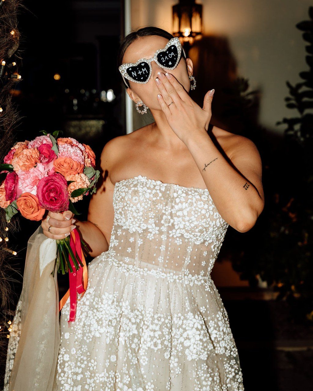 Hochzeitsplanerin Gardasee: lachende Braut mit herzförmiger Sonnenbrille und Brautstrauß in Pink und Orange