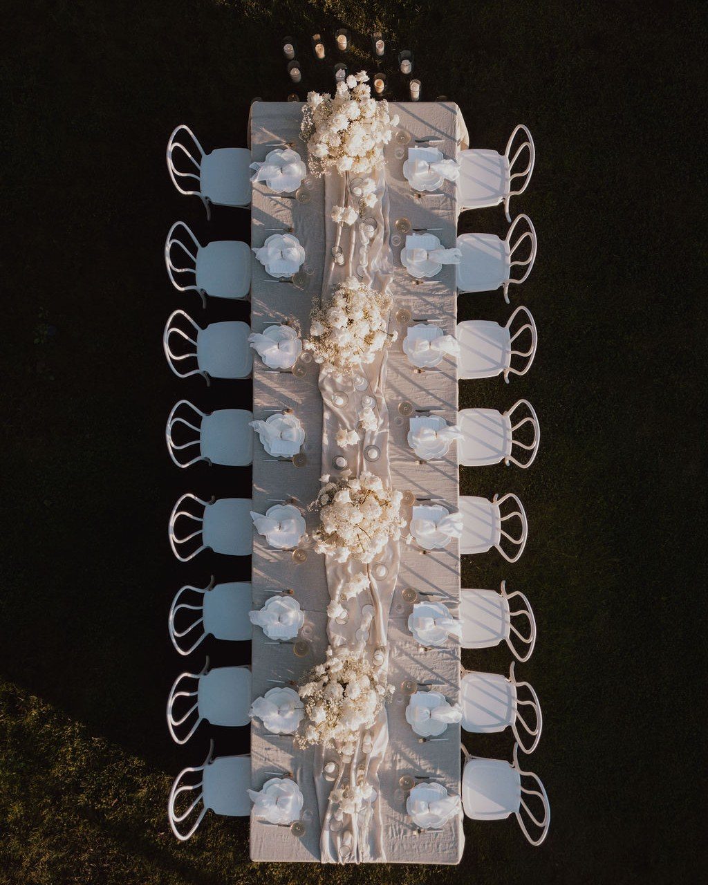 Hochzeitsplanerin Mallorca: lange Tafel von oben mit hellblauen Stühlen und weißem Blumenlauf im Gras