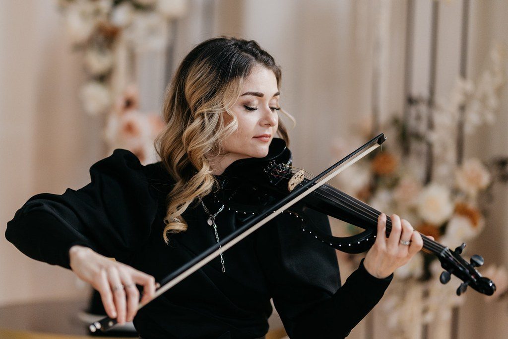 Geigerin in Schwarz spielt vor einer Blütenwand – Live-Musik bei einer von Julia Truisi geplanten Hochzeit in München