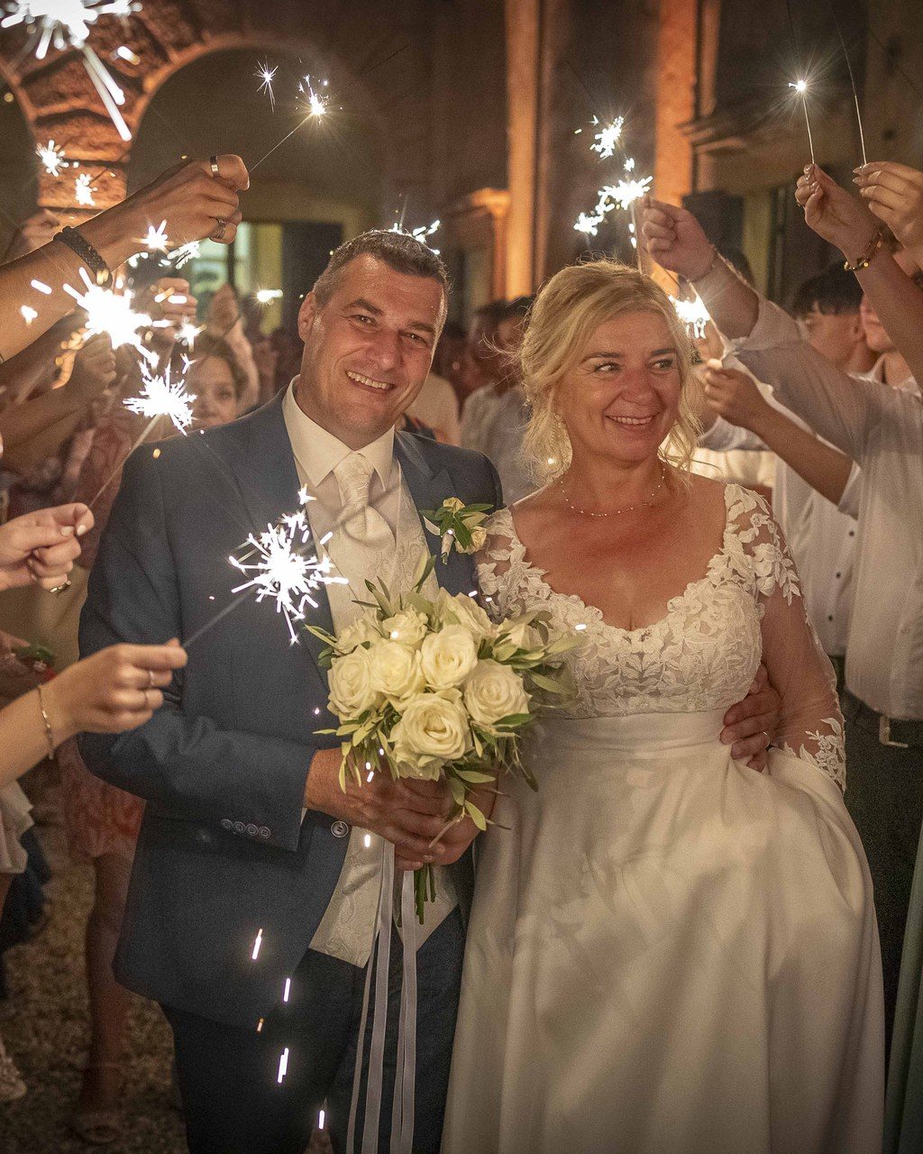 Hochzeitsplanerin Verona: Brautpaar geht abends durch ein Spalier aus Gästen mit Wunderkerzen