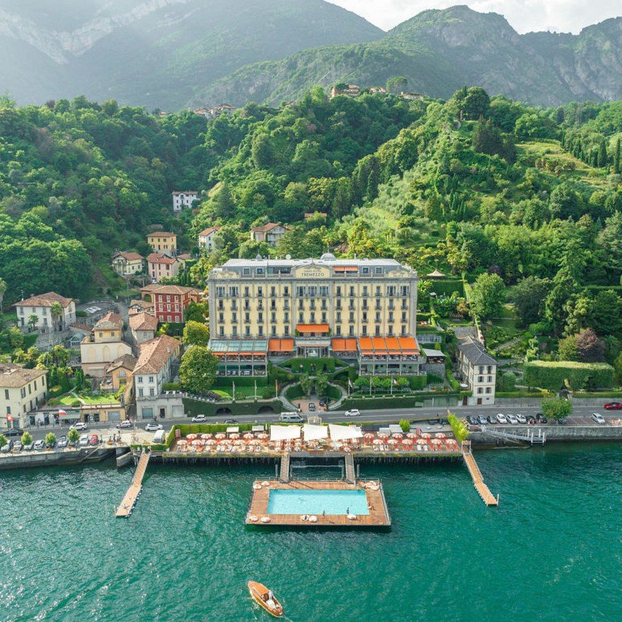 Hochzeitsplanung Comer See: Grandhotel mit schwimmendem Pool direkt am Ufer, dahinter die bewaldeten Berghänge
