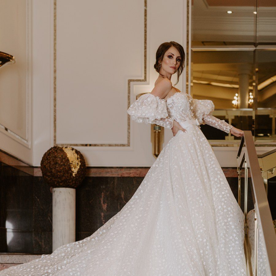 Hochzeitsplanung Schweiz: Braut im Tüllkleid mit langer Schleppe auf der Marmortreppe eines Grandhotels