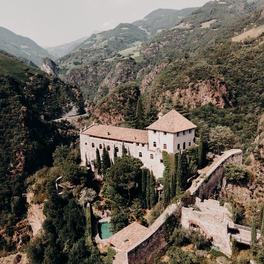 Hochzeitsplanung Südtirol: historisches Schloss auf einem bewaldeten Felsen über dem Tal als Hochzeitslocation
