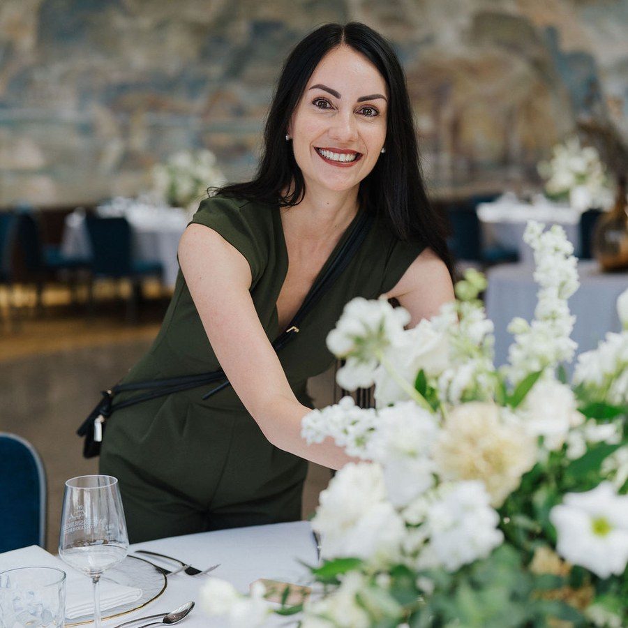 Hochzeitsplanung Tegernsee: Julia Truisi steckt weiße Blumen für das Tafelarrangement zurecht