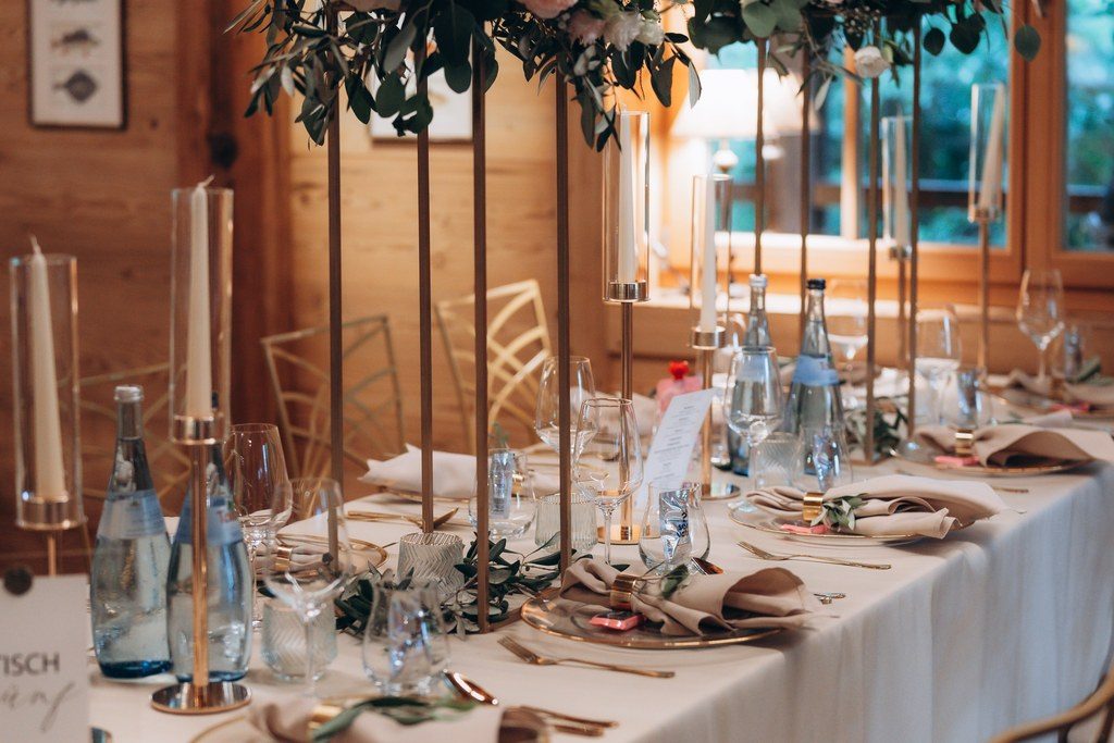 Lange Hochzeitstafel mit hohen Blumenarrangements in Rosé und Kerzen im holzverkleideten Saal