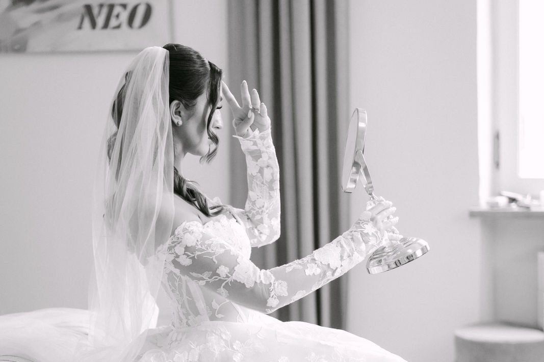 Wedding Planner NRW: Braut beim Getting Ready mit Handspiegel und Spitzenkleid